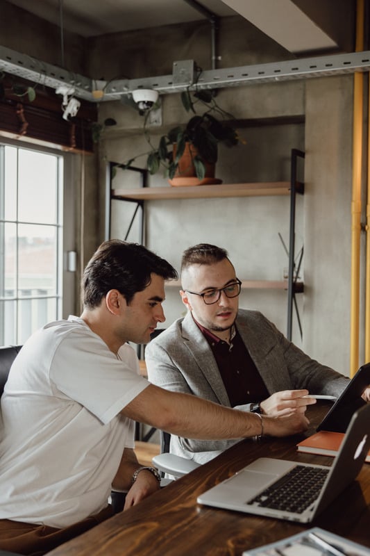 two individuals sitting at a table looking at a laptop